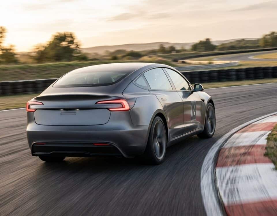 Berline électrique grise en virage rapide sur un circuit au coucher du soleil